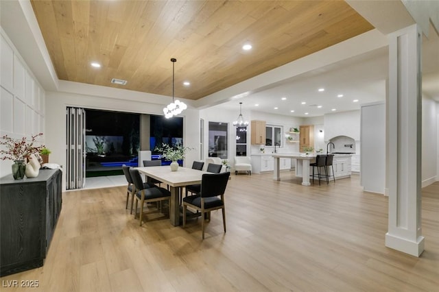 dining space with decorative columns, an inviting chandelier, wood ceiling, and light hardwood / wood-style floors