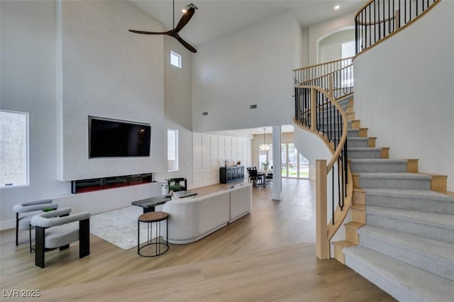 living room featuring plenty of natural light, light hardwood / wood-style flooring, and a high ceiling