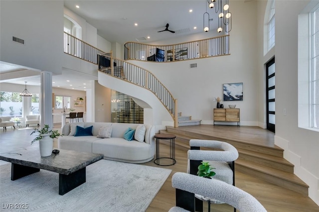 living room featuring a notable chandelier, a towering ceiling, and light wood-type flooring