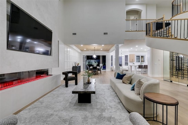 living room with a towering ceiling and light wood-type flooring