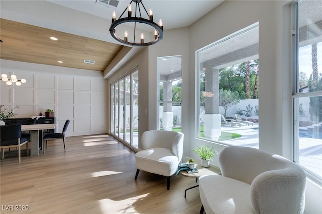 sitting room featuring an inviting chandelier, light wood-type flooring, and wooden ceiling