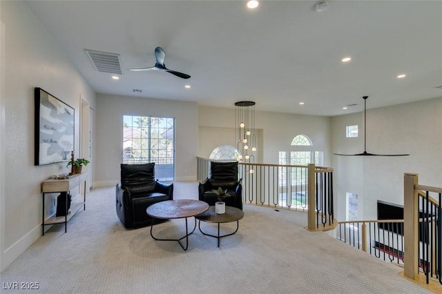 sitting room with ceiling fan with notable chandelier and light carpet