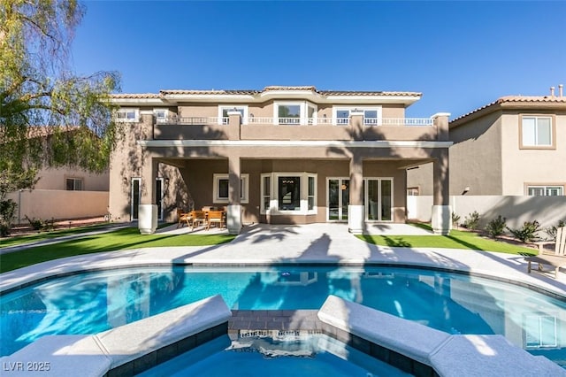 rear view of property featuring a pool with hot tub, ceiling fan, a patio area, and a balcony