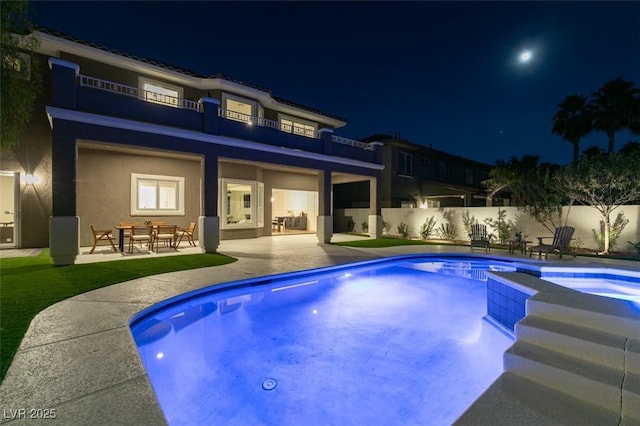 pool at twilight with an in ground hot tub and a patio