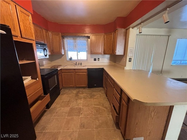 kitchen featuring black appliances, sink, light tile patterned floors, and kitchen peninsula