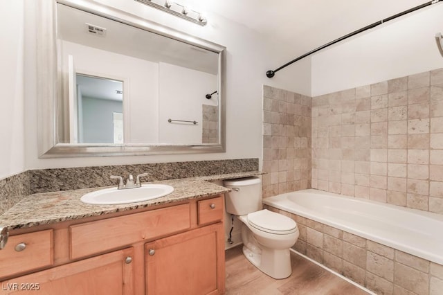 full bathroom featuring tiled shower / bath combo, wood-type flooring, vanity, and toilet