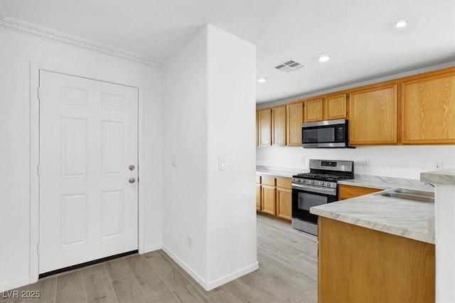 kitchen with sink, ornamental molding, stainless steel appliances, and light hardwood / wood-style floors