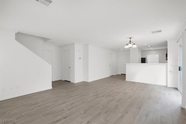 unfurnished living room featuring a chandelier and light wood-type flooring