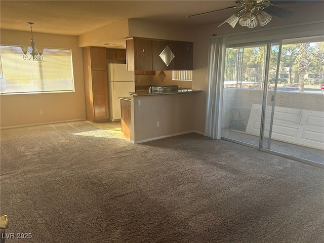 kitchen featuring light carpet, ceiling fan with notable chandelier, kitchen peninsula, and white refrigerator