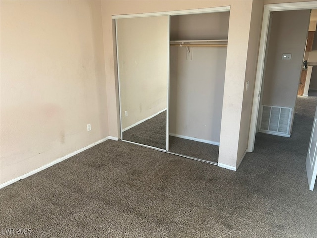 unfurnished bedroom featuring dark colored carpet and a closet