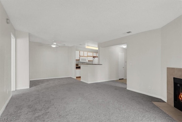 unfurnished living room with ceiling fan, a fireplace, carpet, and a textured ceiling