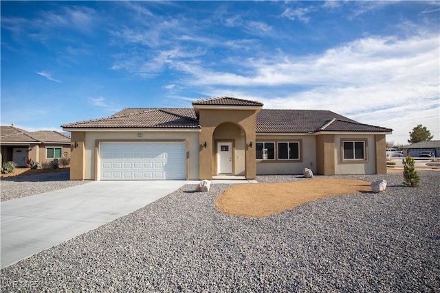 view of front facade featuring an attached garage, a tiled roof, concrete driveway, and stucco siding