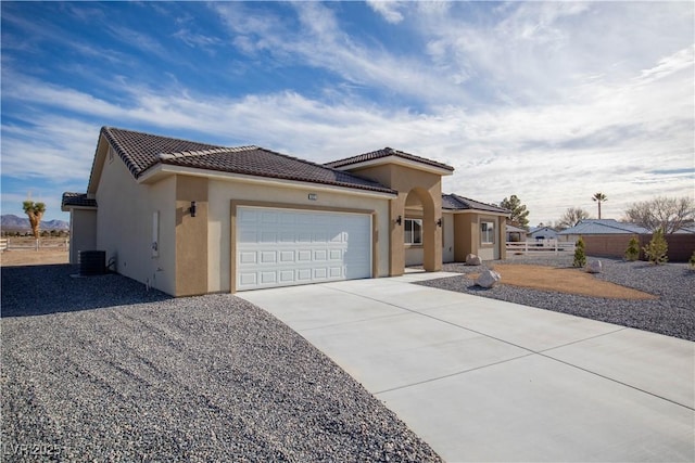 view of front of property with a tile roof, stucco siding, concrete driveway, an attached garage, and central AC unit