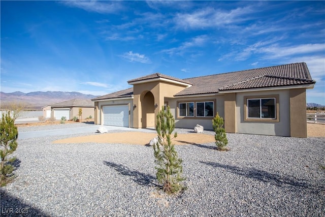 mediterranean / spanish-style home featuring an attached garage, a mountain view, a tile roof, concrete driveway, and stucco siding