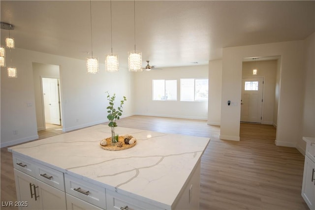 kitchen featuring white cabinets, open floor plan, light wood-type flooring, a center island, and pendant lighting