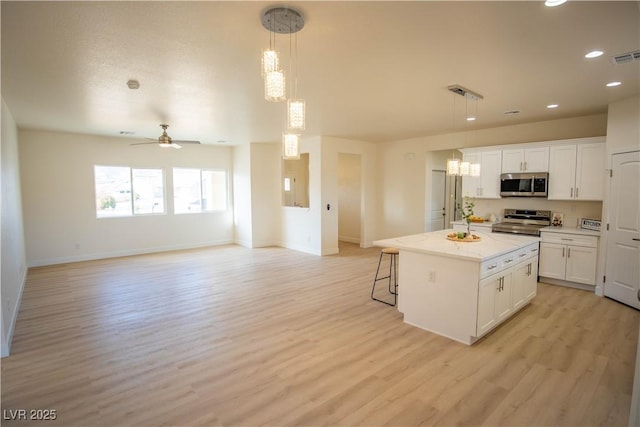 kitchen featuring open floor plan, appliances with stainless steel finishes, a kitchen island, and pendant lighting