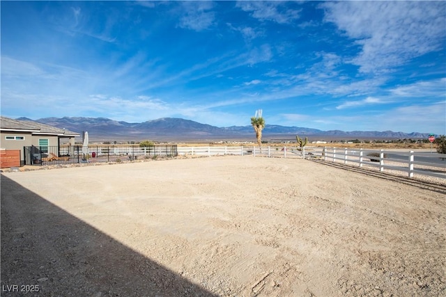 view of yard featuring an enclosed area, fence, a mountain view, and a rural view