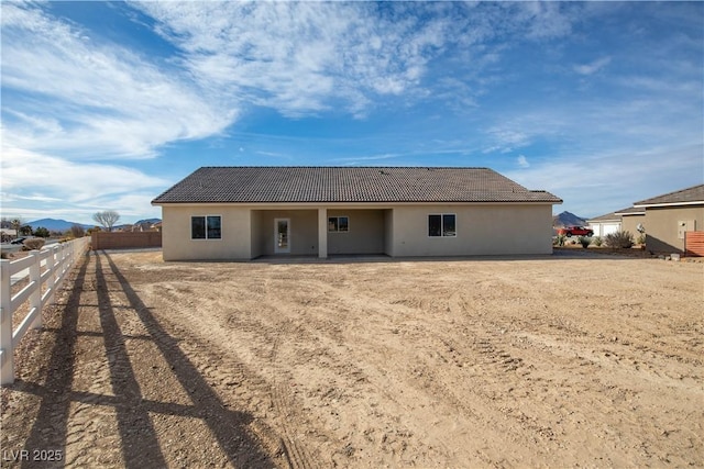 rear view of property featuring a tiled roof, a fenced backyard, and stucco siding