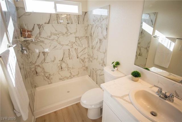 bathroom featuring vanity, wood finished floors, a shower stall, and toilet