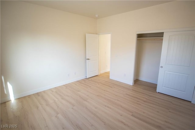 unfurnished bedroom with light wood-type flooring, a closet, and baseboards