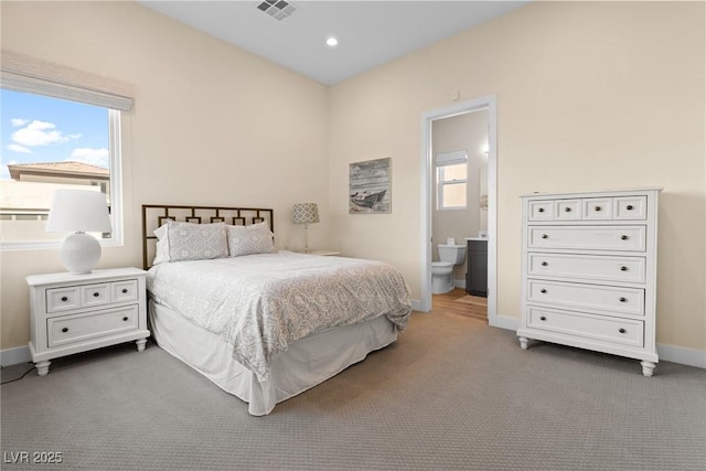 bedroom with ensuite bathroom and carpet