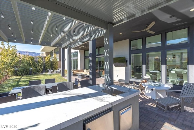 view of patio featuring an outdoor wet bar, an outdoor hangout area, ceiling fan, and a pergola