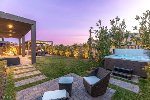 yard at dusk with an outdoor living space, a hot tub, and a patio area