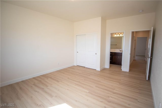 unfurnished bedroom with a closet, baseboards, and light wood-style floors