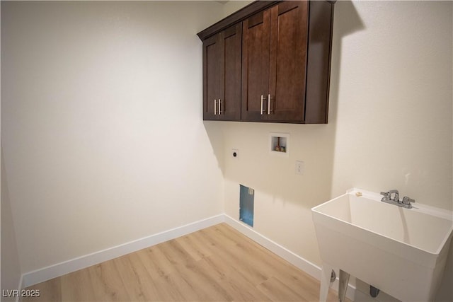 laundry area featuring light wood finished floors, baseboards, washer hookup, cabinet space, and a sink