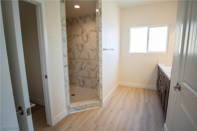 bathroom featuring a marble finish shower, baseboards, recessed lighting, wood finished floors, and vanity