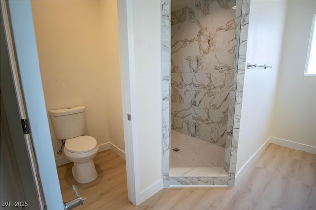 bathroom with a marble finish shower, toilet, baseboards, and wood finished floors