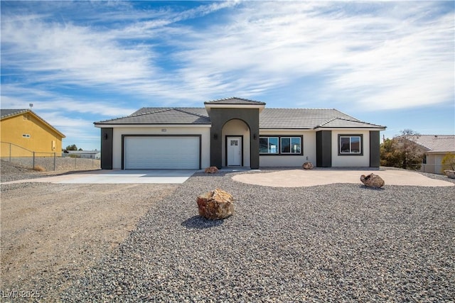 view of front of house with stucco siding, driveway, fence, a garage, and a tiled roof