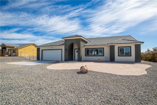 ranch-style house with fence, an attached garage, stucco siding, concrete driveway, and a tiled roof