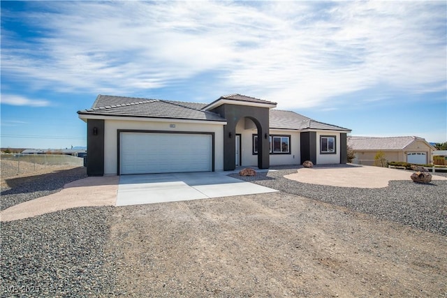 view of front of home with a tile roof, stucco siding, an attached garage, and concrete driveway