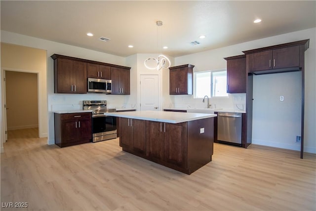 kitchen with visible vents, a sink, a kitchen island, dark brown cabinetry, and appliances with stainless steel finishes