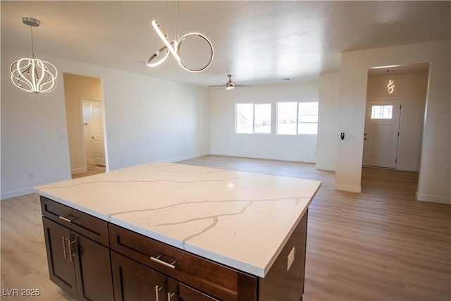 kitchen featuring plenty of natural light, a kitchen island, light wood-style flooring, and hanging light fixtures