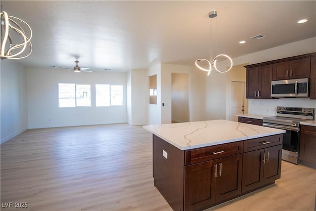 kitchen featuring decorative light fixtures, stainless steel appliances, a center island, and ceiling fan with notable chandelier