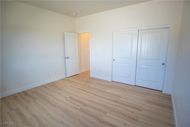 unfurnished bedroom with a closet, baseboards, and light wood finished floors