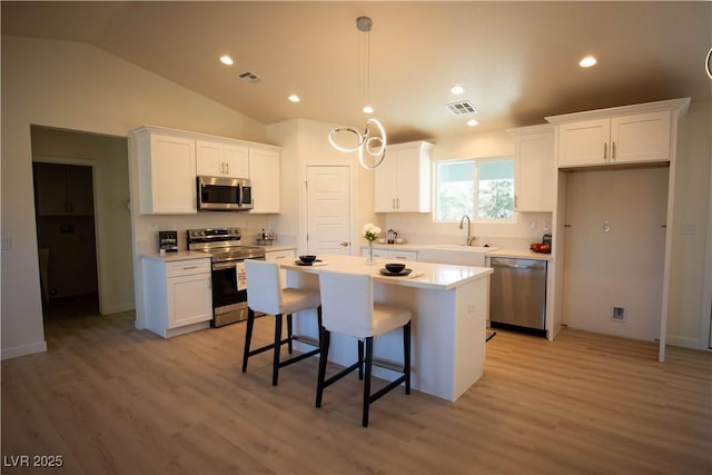 kitchen featuring stainless steel appliances, a kitchen island, visible vents, white cabinetry, and light countertops