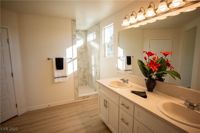 bathroom with baseboards, a walk in shower, a sink, and wood finished floors