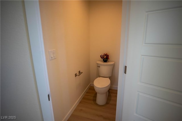 bathroom with wood finished floors, toilet, and baseboards