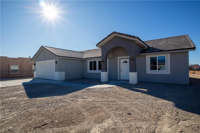 ranch-style home featuring a garage, a tiled roof, and stucco siding