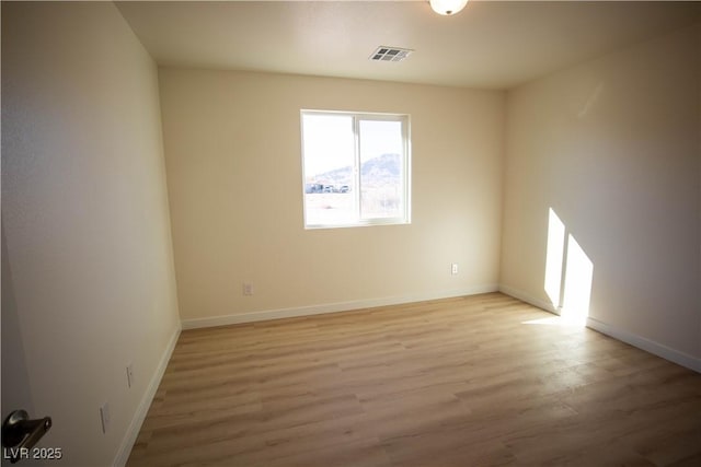 spare room with light wood-style floors, baseboards, and visible vents