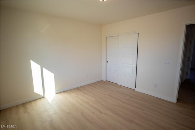 unfurnished bedroom with a closet, light wood-style flooring, and baseboards