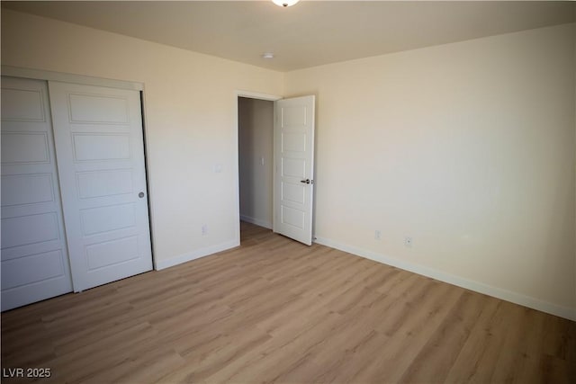 unfurnished bedroom featuring light wood finished floors, baseboards, and a closet