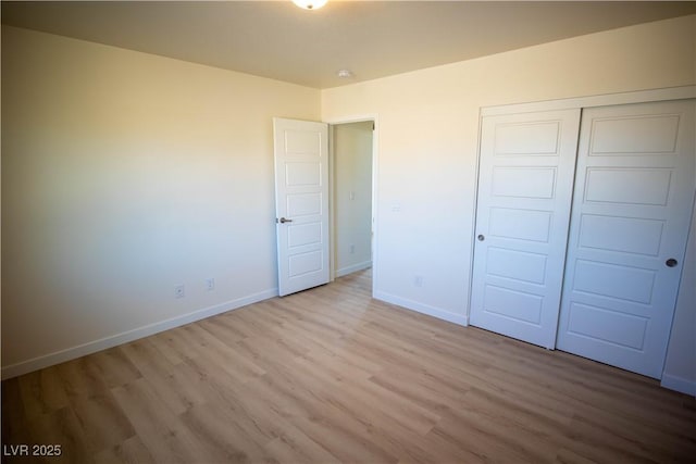 unfurnished bedroom with a closet, light wood-type flooring, and baseboards