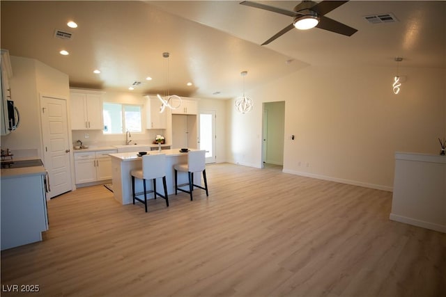 kitchen with visible vents, light countertops, white cabinetry, and a center island