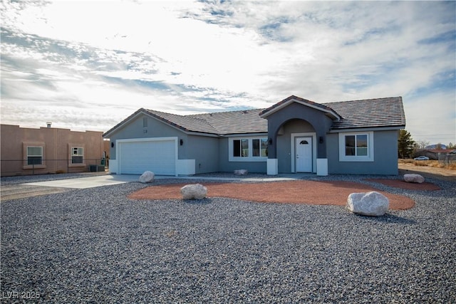 ranch-style home featuring a tile roof, an attached garage, driveway, and stucco siding