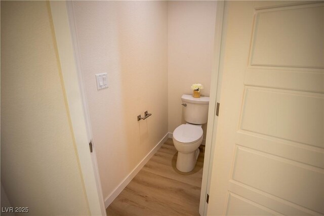 bathroom with baseboards, toilet, and wood finished floors