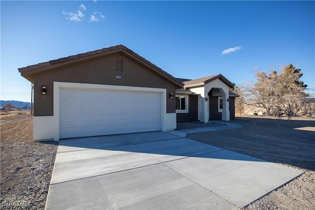 single story home featuring concrete driveway, a tile roof, an attached garage, and stucco siding